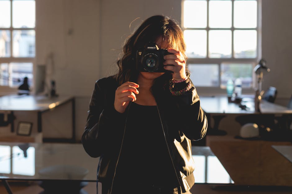 A woman photographer captures a moment indoors with a camera, bathed in warm sunlight.